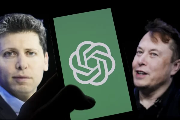 The logo of OpenAI is shown on a mobile phone in front of a computer screen displaying the photographs of Sam Altman, left, and Elon Musk,